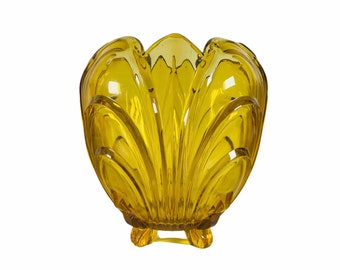 May include: A yellow glass vase with a scalloped design and three legs.