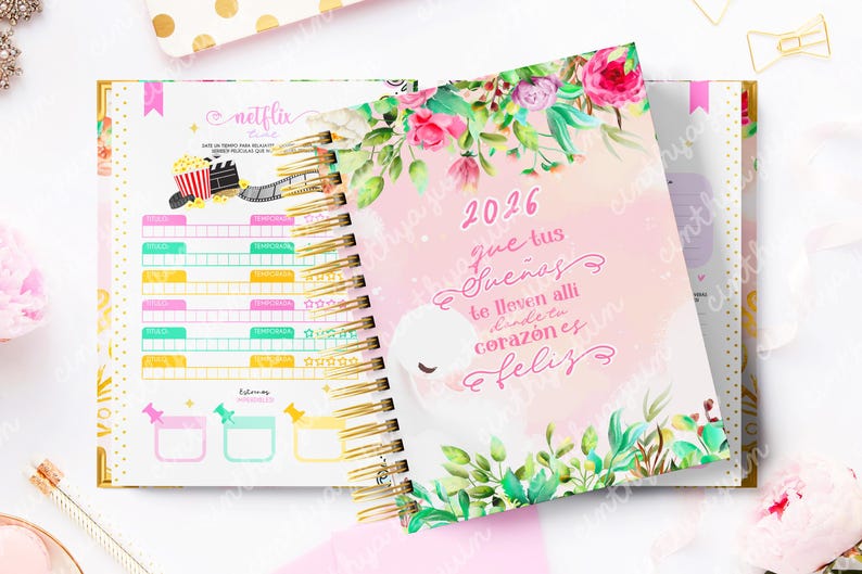 May include: Open spiral-bound planner with a floral cover featuring the year 2026 and a swan illustration. The planner's interior includes sections for Netflix tracking and goal setting, with a gold spiral binding and a pink and gold color scheme.