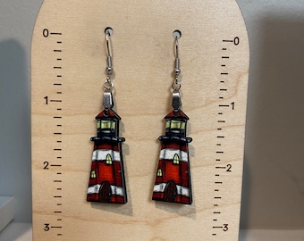 May include: Pair of wooden lighthouse earrings with red, white, and black stripes. The earrings are about 2 inches long and have silver hooks.
