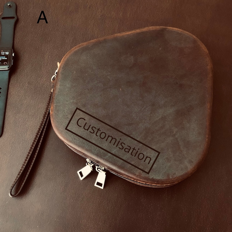 May include: A brown leather zippered pouch with a strap. The pouch has the word "Customisation" embossed on the front.
