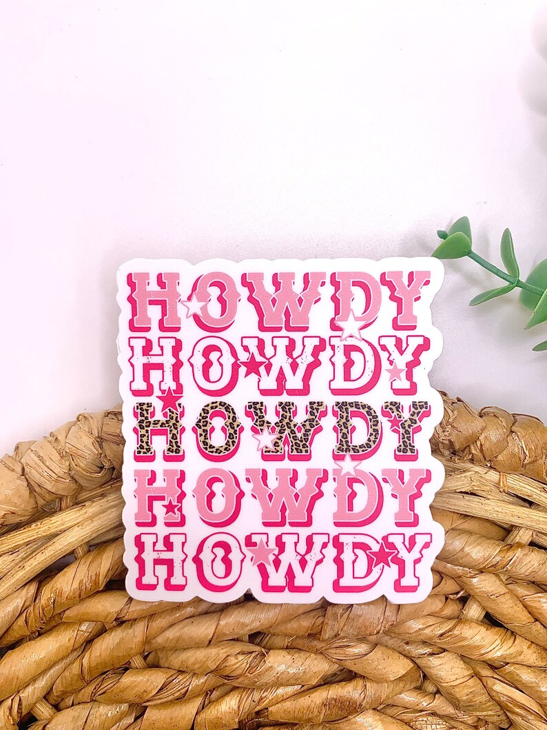 May include: Pink and white sticker with the word "Howdy" repeated five times in a stacked design. Each word has a different design, with some featuring leopard print and stars.