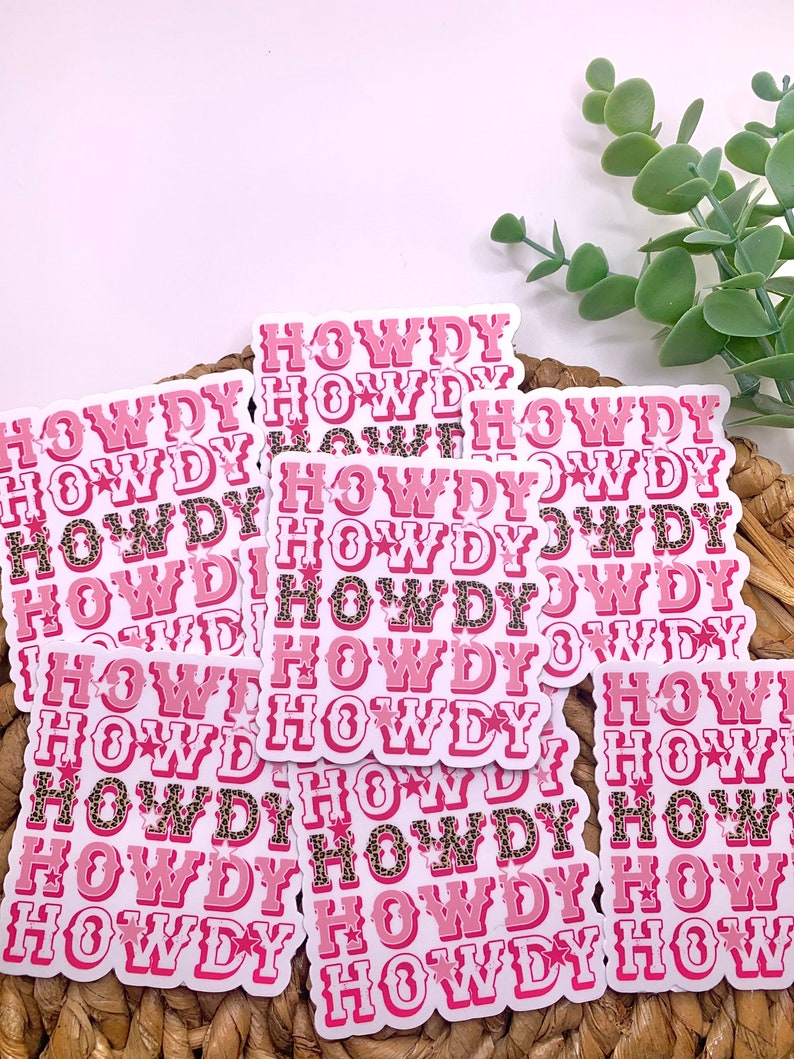 May include: A stack of pink and white stickers with the word "HOWDY" repeated multiple times. The stickers have a leopard print pattern and a star design.