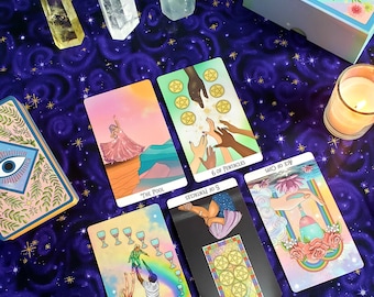 May include: A tarot card reading spread with six cards laid out on a purple cloth with stars. The cards are The Fool, 5 of Pentacles, 6 of Pentacles, Ace of Cups, 10 of Cups, and The Mystic Soul Tarot Deck box.