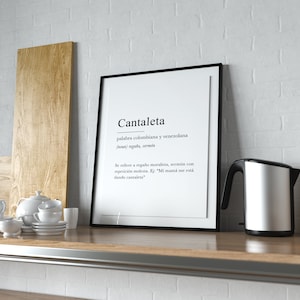 May include: A black framed print with the word "Cantaleta" in white text. The definition of the word is in Spanish and reads "palabra colombiana y venezolana (noun) rega&ntilde;a, serm&oacute;n Se refiere a rega&ntilde;o moralista, serm&oacute;n con repetici&oacute;n molesta. Ej: "Mi mam&aacute; me est&aacute; dando cantaleta"