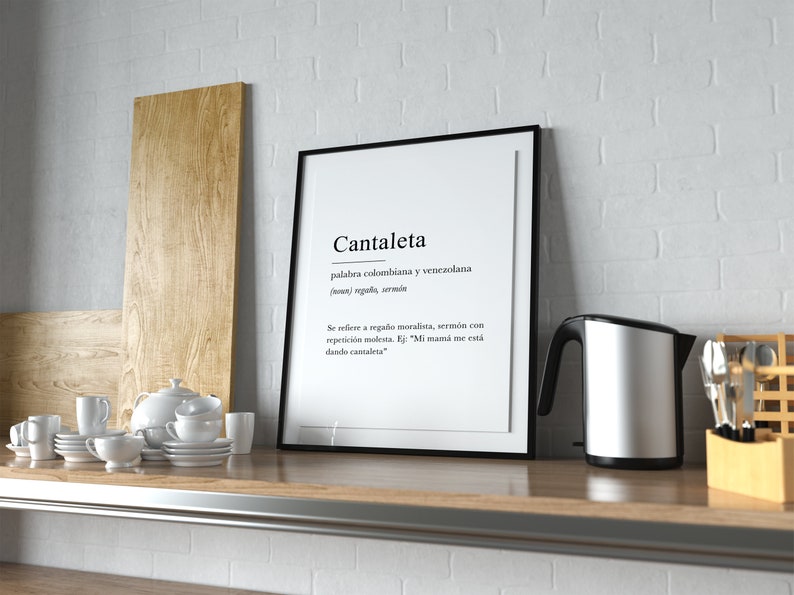 May include: A black framed print with the word "Cantaleta" in white text. The definition of the word is in Spanish and reads "palabra colombiana y venezolana (noun) rega&ntilde;a, serm&oacute;n Se refiere a rega&ntilde;o moralista, serm&oacute;n con repetici&oacute;n molesta. Ej: "Mi mam&aacute; me est&aacute; dando cantaleta"