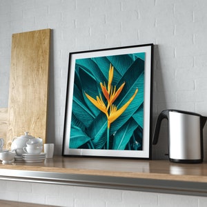 Puede incluir: Una impresi&oacute;n enmarcada de una flor tropical amarilla con hojas verdes. La impresi&oacute;n est&aacute; colgada en una pared de ladrillo blanco sobre una encimera de madera.