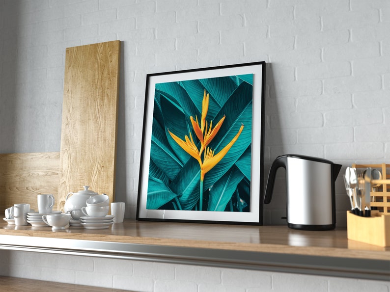 Puede incluir: Una impresi&oacute;n enmarcada de una flor tropical amarilla con hojas verdes. La impresi&oacute;n est&aacute; colgada en una pared de ladrillo blanco sobre una encimera de madera.