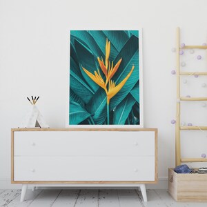 Puede incluir: Una impresi&oacute;n enmarcada de una flor de ave del para&iacute;so amarilla con hojas verdes. La impresi&oacute;n est&aacute; colgada en una pared blanca sobre una c&oacute;moda blanca con dos cajones.