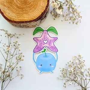 May include: A blue and purple cartoon sticker of a character holding a star-shaped flower. The character has a round body, two small arms, and a small green sprout on top of its head. The star-shaped flower is purple with a white heart in the center.