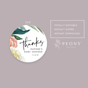 May include: A round, 2-inch thank you sticker with a floral design in shades of pink, white, and green. The text "Thanks" is written in black cursive script. The text "Daphne's Baby Shower 11.12.21" is written in black sans-serif font.
