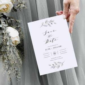 Op de afbeelding: Save the date-kaart met een aquarelbloemendesign. De kaart is wit met zwarte tekst en luidt "Save the Date" voor de bruiloft van Elise en William op zaterdag 26 augustus 2021 in Melbourne, Victoria. Formele uitnodiging volgt.