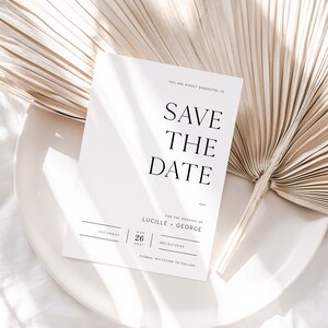 Op de afbeelding: Een witte save-the-date kaart met zwarte tekst. De tekst luidt: "U wordt vriendelijk verzocht de datum voor de bruiloft van Lucille en George te reserveren, zaterdag 26 augustus 2021, Melbourne. Formele uitnodiging volgt."