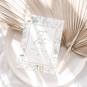 Op de afbeelding: Save the date huwelijksuitnodiging met een gouden frame en groene aquarelbladeren. De uitnodiging zegt "Save the date" voor het huwelijk van Amanda en Harry op zaterdag 26 augustus 2021 in Melbourne.