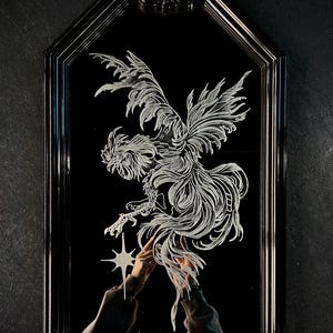 May include: Black framed mirror with a detailed white etched design of a phoenix. The phoenix is reaching for a star. The mirror has a decorative top and is set against a dark background.