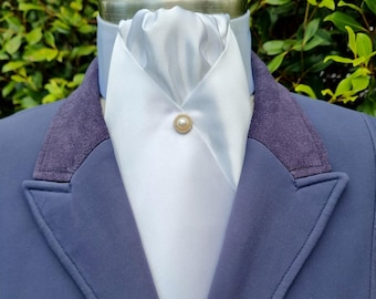 May include: A navy blue equestrian jacket with a white stock tie and a pearl pin. The jacket has a purple velvet collar and a tailored fit, suitable for riding or formal events.