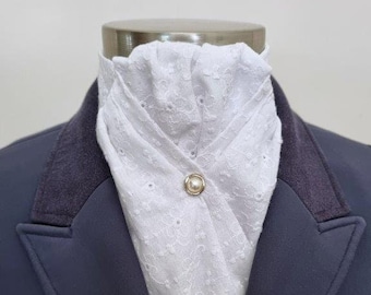 May include: White cotton cravat with eyelet embroidery and a pearl button. The cravat is worn with a dark blue jacket.