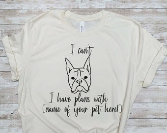 Op de afbeelding: Een wit T-shirt met een zwarte omtrek van een Franse Bulldog en de tekst "Ik kan niet Ik heb plannen met [naam van je huisdier hier!]".