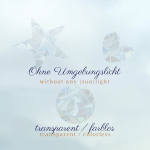 May include: Three transparent, iridescent window clings in the shapes of a star, a heart, and a circle. The clings are made of a mosaic-like material. Text on the image reads "Ohne Umgebungslicht without any (sun)light" and "transparent / farblos transparent / colorless."