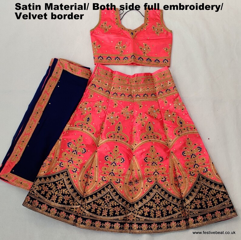 May include: A pink and blue embroidered Indian bridal outfit with a velvet border. The outfit includes a long skirt, a sleeveless blouse, and a matching dupatta.
