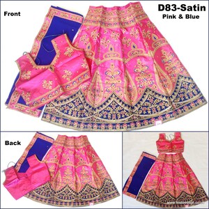 May include: A pink and blue Indian girls' lehenga choli set with gold embroidery. The skirt is pink with a blue and gold border. The choli is pink with gold embroidery. The dupatta is blue with a gold border. The set is called "D83-Satin Pink & Blue".