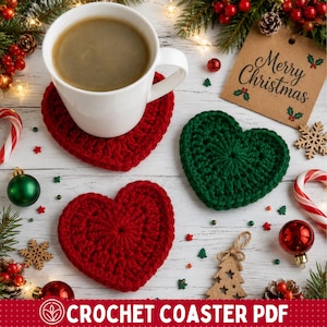 Könnte beinhalten: Zwei rote und ein grüner herzförmiger Häkeluntersetzer. Auf einem roten Untersetzer steht eine weiße Keramiktasse mit Kaffee. Ein braunes Papieretikett mit der Aufschrift Merry Christmas ist zu sehen. Die Untersetzer haben ein gehäkeltes Muster.
