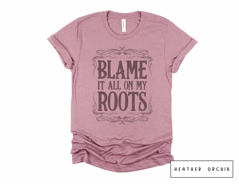May include: A heather orchid t-shirt with a vintage-style graphic that says "Blame it all on my roots".