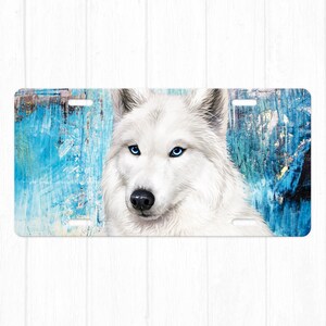 May include: A white wolf with blue eyes against a blue and yellow abstract background. The wolf is looking directly at the viewer.