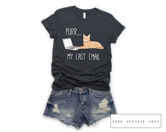 May include: Dark heather gray t-shirt with a white graphic of a cat sitting on a laptop with the text "Purr... My Last Email".