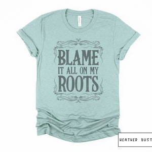 May include: A light blue t-shirt with a vintage-style graphic that says "Blame it all on my roots".