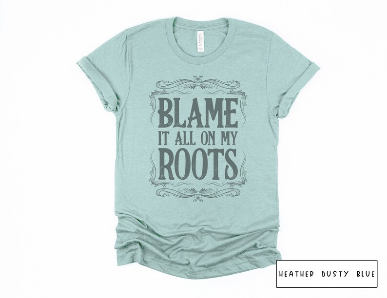 May include: A light blue t-shirt with a vintage-style graphic that says "Blame it all on my roots".