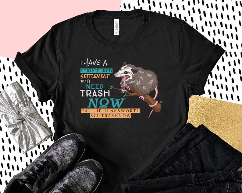 K&ouml;nnte beinhalten: Schwarzes T-Shirt mit einem Grafikdruck eines Opossums, das einen Ast h&auml;lt, mit dem Text "Ich habe eine strukturierte Regelung, aber ich brauche jetzt M&uuml;ll. Rufen Sie JP Junksworth 877-Trashnow an."