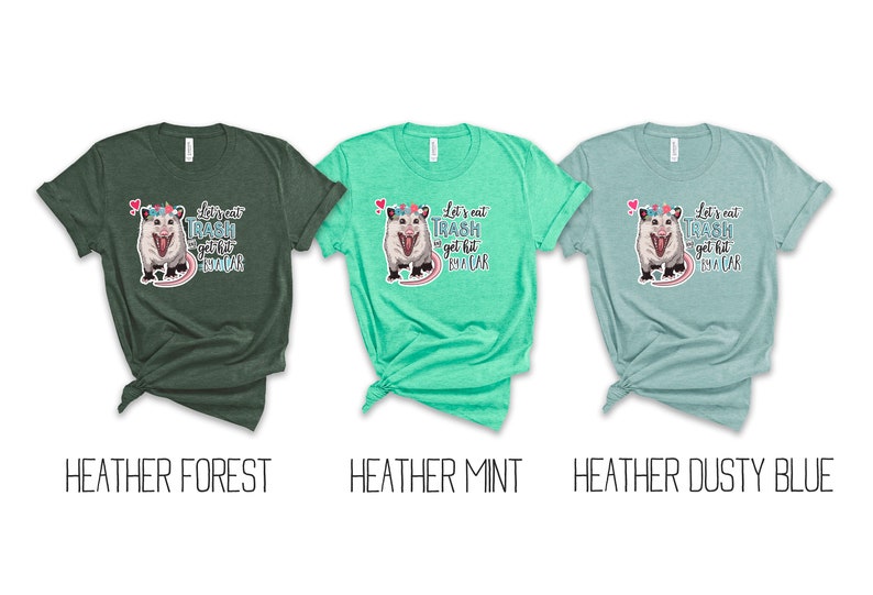 May include: Three heathered t-shirts in forest green, mint, and dusty blue. Each shirt features a graphic of an opossum with a floral crown and the text "Let's eat trash get hit by a car".