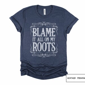 May include: A heather midnight navy t-shirt with the text "Blame it all on my roots" in a vintage-style font.