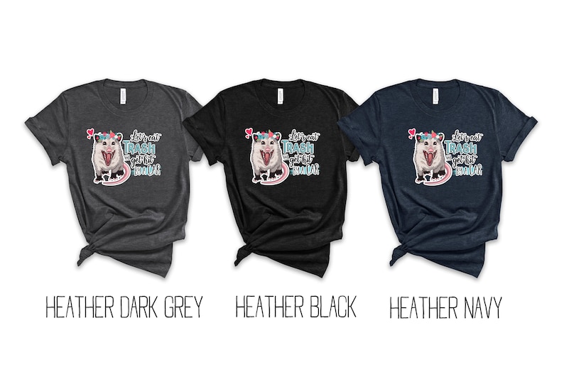 May include: Three t-shirts in heather dark grey, heather black, and heather navy. Each shirt features a graphic of an opossum with a unicorn horn and the text "let's eat trash and get hit by a car".