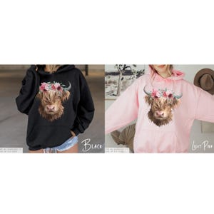 Puede incluir: Dos sudaderas con capucha para mujer con una vaca de las Tierras Altas con una corona de flores impresa en la parte delantera. La sudadera con capucha de la izquierda es negra y la de la derecha es rosa claro.