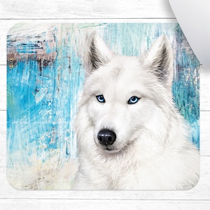 May include: A white wolf with blue eyes is depicted against a blue and white abstract background. The wolf's fur is soft and fluffy, and its eyes are piercing.