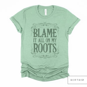 May include: A heather mint green t-shirt with a vintage-style graphic that says "Blame it all on my roots".