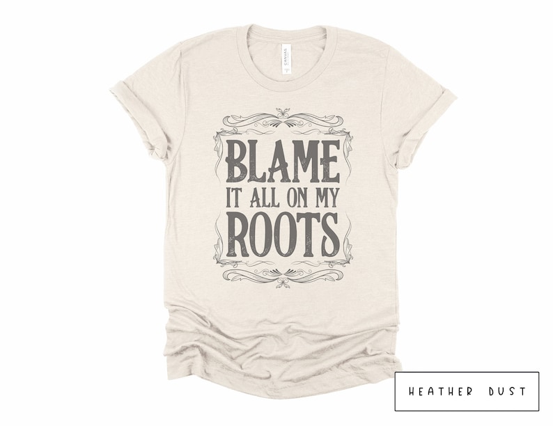 May include: A beige t-shirt with a vintage-style graphic that says "Blame it all on my roots".