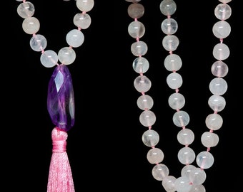 May include: A pink and white mala necklace with a purple amethyst pendant and a pink tassel. The necklace is made of round beads and is approximately 108 beads long.