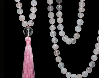 May include: A pink and white mala necklace with a pink tassel. The necklace is made of round beads and is approximately 108 beads long.