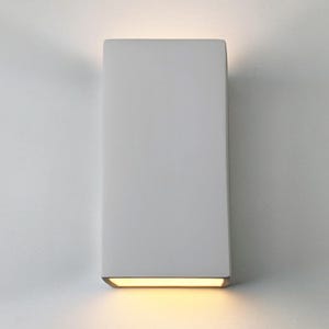 May include: A white rectangular wall sconce with a warm white light emanating from the bottom edge.