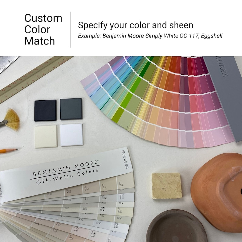 May include: A color chart with a variety of paint colors, including off-white, beige, and gray. The chart is labeled "Benjamin Moore Off-White Colors". There are also paint chips, a paint brush, a pencil, and a small terracotta pot.