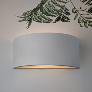 May include: A white, curved, wall-mounted light fixture with a soft, warm glow.