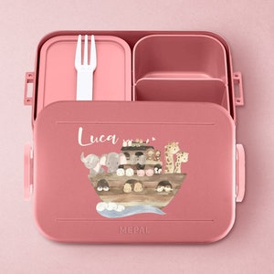 Puede incluir: Lonchera rosa con tapa extra&iacute;ble y un tenedor. La lonchera tiene un compartimento para un s&aacute;ndwich y un compartimento m&aacute;s peque&ntilde;o para refrigerios. La lonchera tiene una ilustraci&oacute;n colorida de un barco con animales. La lonchera tiene el nombre "Luca" escrito en ella.