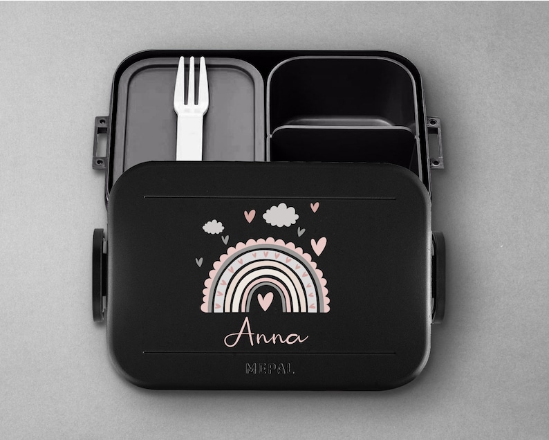 May include: Black lunchbox with a rainbow and clouds design. The lunchbox has a removable fork and a personalized name, "Anna".