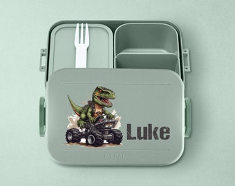 May include: Green lunchbox with a dinosaur riding a vehicle and the name Luke on the front. The lunchbox has a removable fork and two compartments.