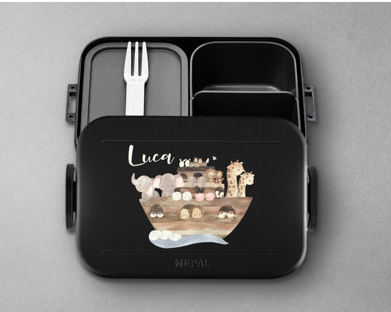 Puede incluir: Lonchera negra con tapa extra&iacute;ble y un tenedor en el interior. La lonchera tiene una ilustraci&oacute;n colorida de animales en un barco con el nombre "Luca" impreso en la parte delantera. La lonchera es de la marca "MEPAL".
