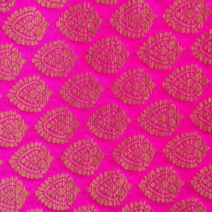 May include: A vibrant hot pink fabric featuring a repeating pattern of metallic gold leaf-shaped motifs. Each gold leaf design is filled with intricate, fine line details, creating a textured appearance against the bright pink background.