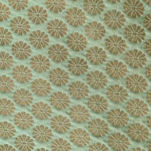May include: A light mint green fabric featuring a repeating pattern of small, woven golden-brown floral motifs. The textile has a visible, slightly textured weave with a consistent grid of circular flower shapes distributed across the surface.