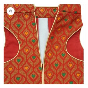 May include: A sleeveless waistcoat in a vibrant red fabric featuring a repeating gold diamond pattern with small green and orange heart-shaped accents. The garment includes gold piping along the armholes and front opening, with a white inner lining.
